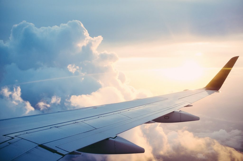 Ala di un aereo di linea in volo sopra le nuvole al tramonto