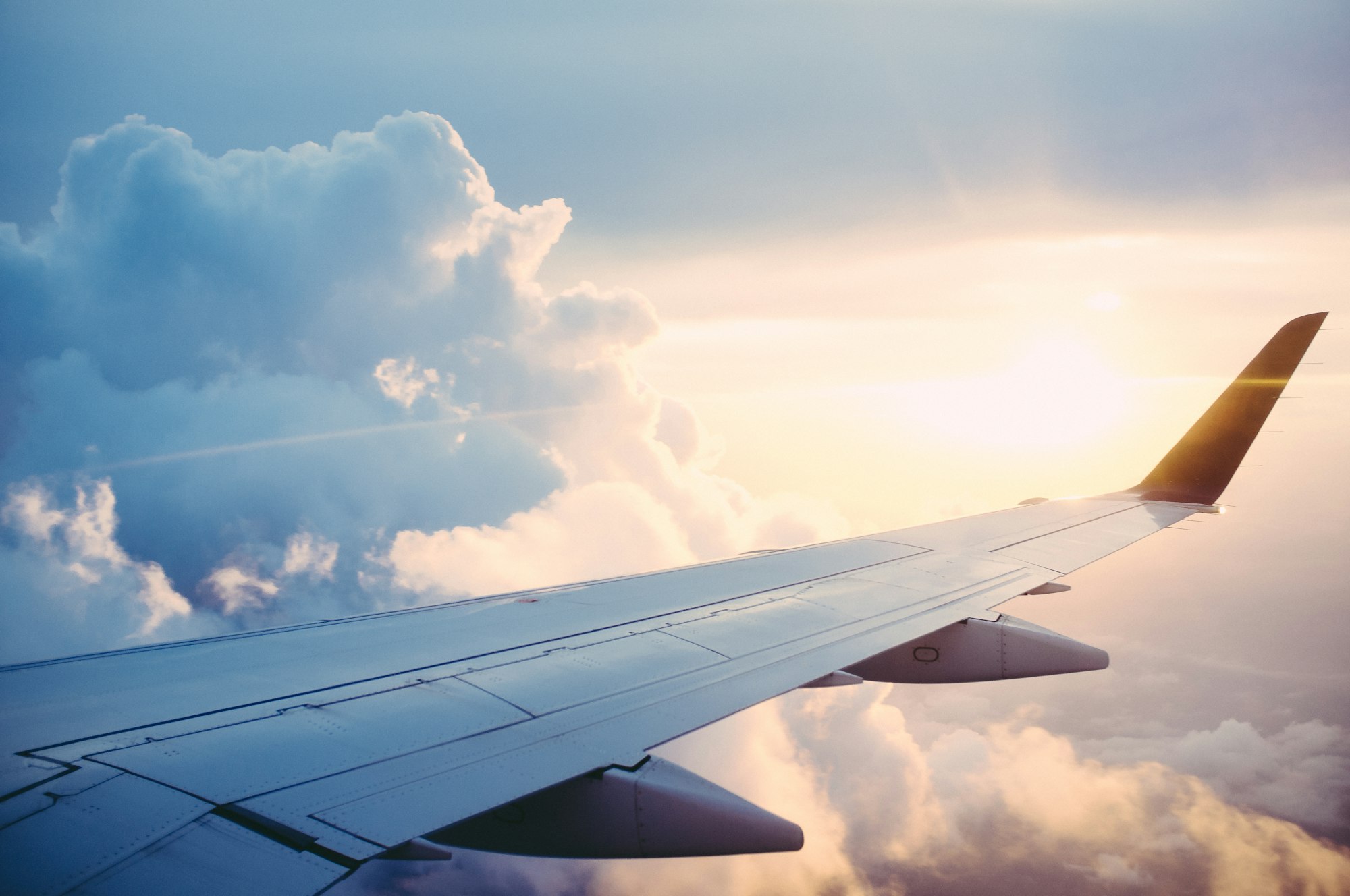 Ala di un aereo di linea in volo sopra le nuvole al tramonto
