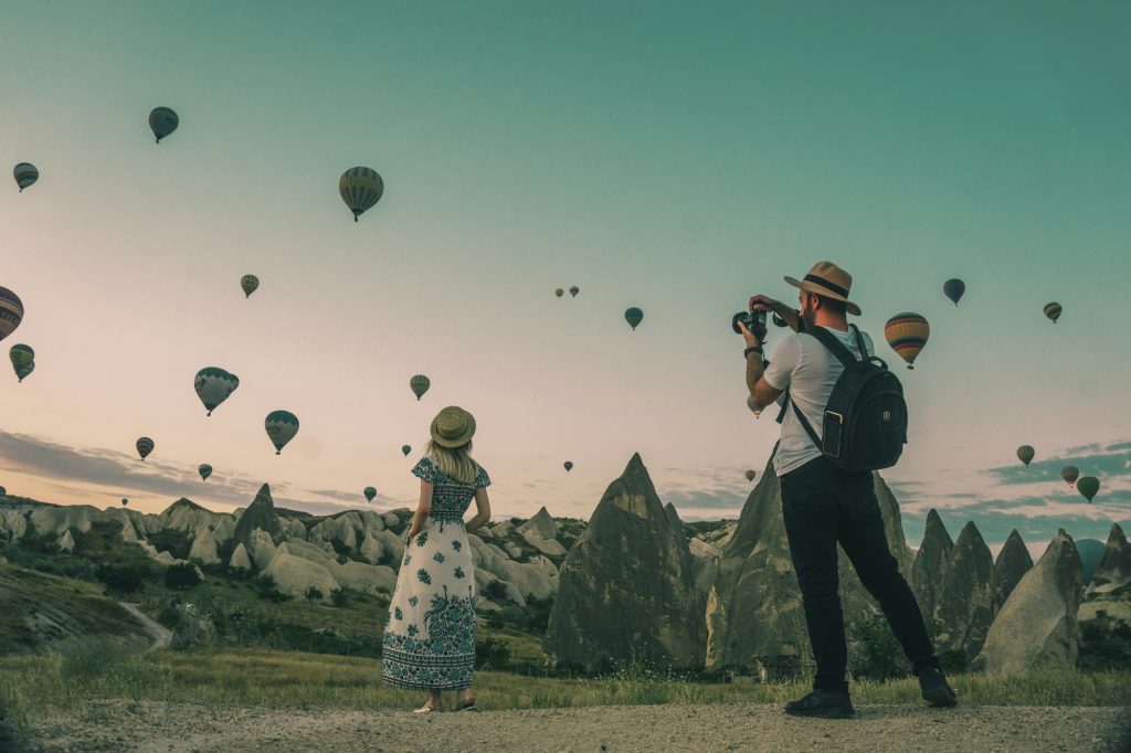 Mongolfiere all'alba sulla Cappadocia, con due viaggiatori che fotografano il panorama
