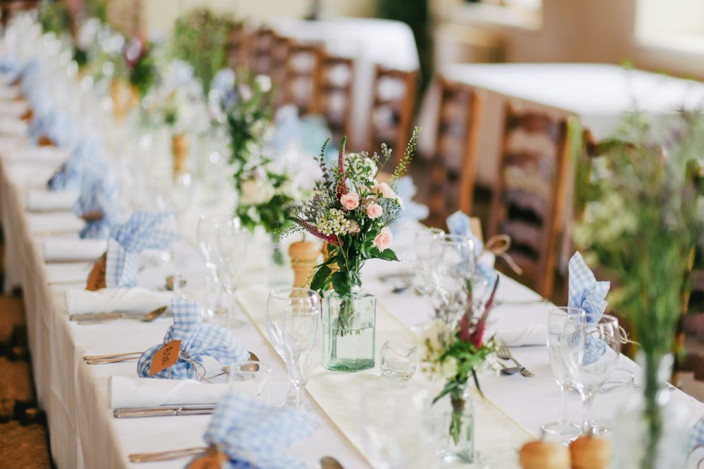 Tavolo del ricevimento di matrimonio apparecchiato con fiori di campo e dettagli azzurri